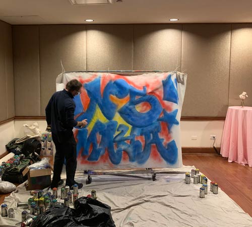 man spray painting onto canvas