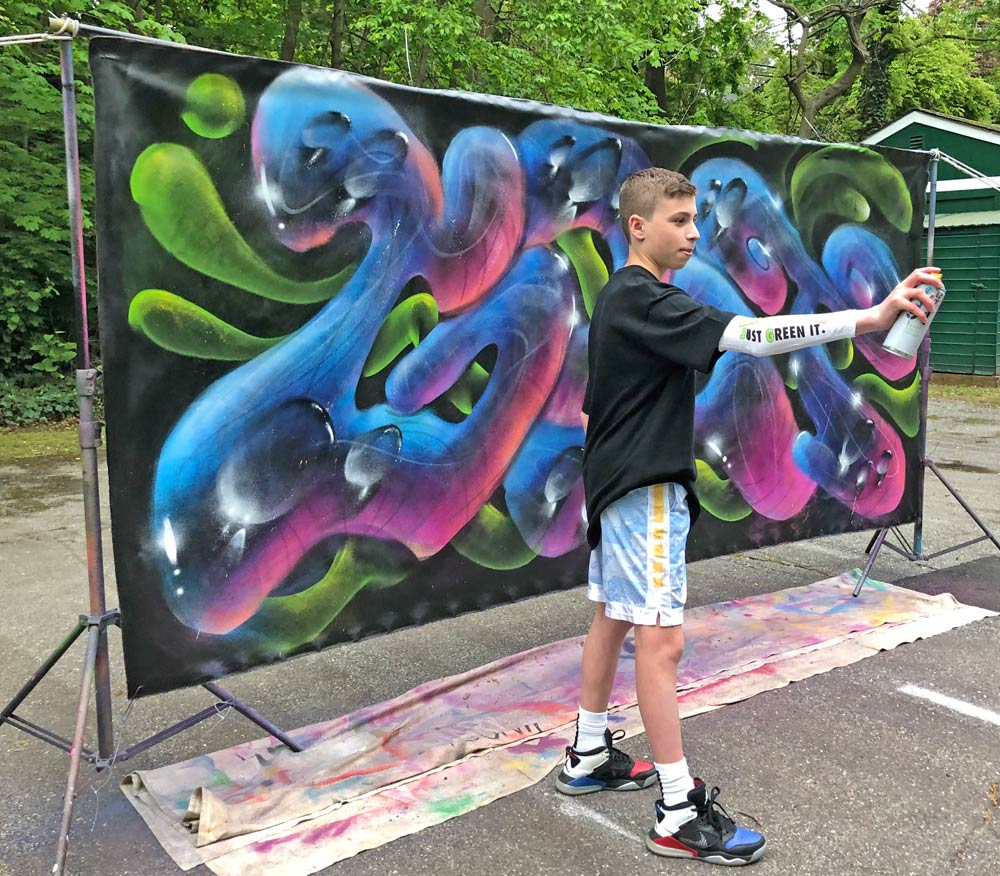 Teen standing in front of graffiti canvas