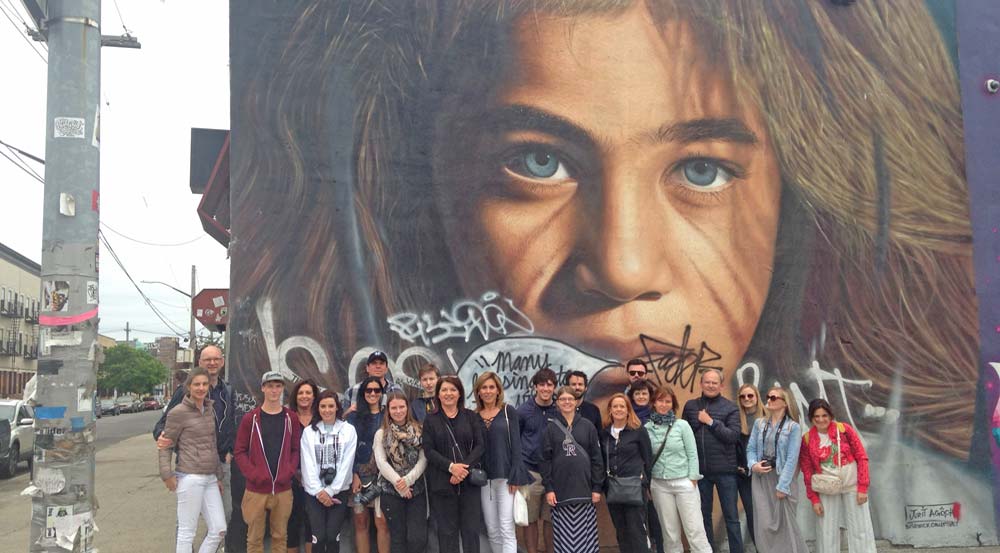 Tour group posing in front of mural artwork